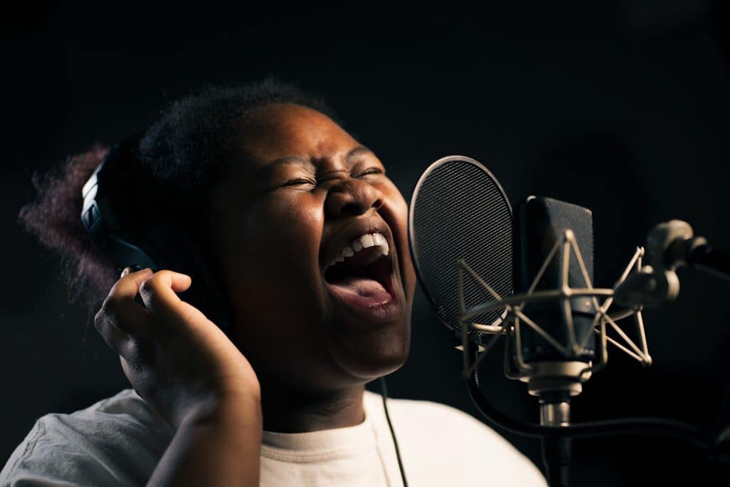 Woman singing into a microphone at a recording arts school.