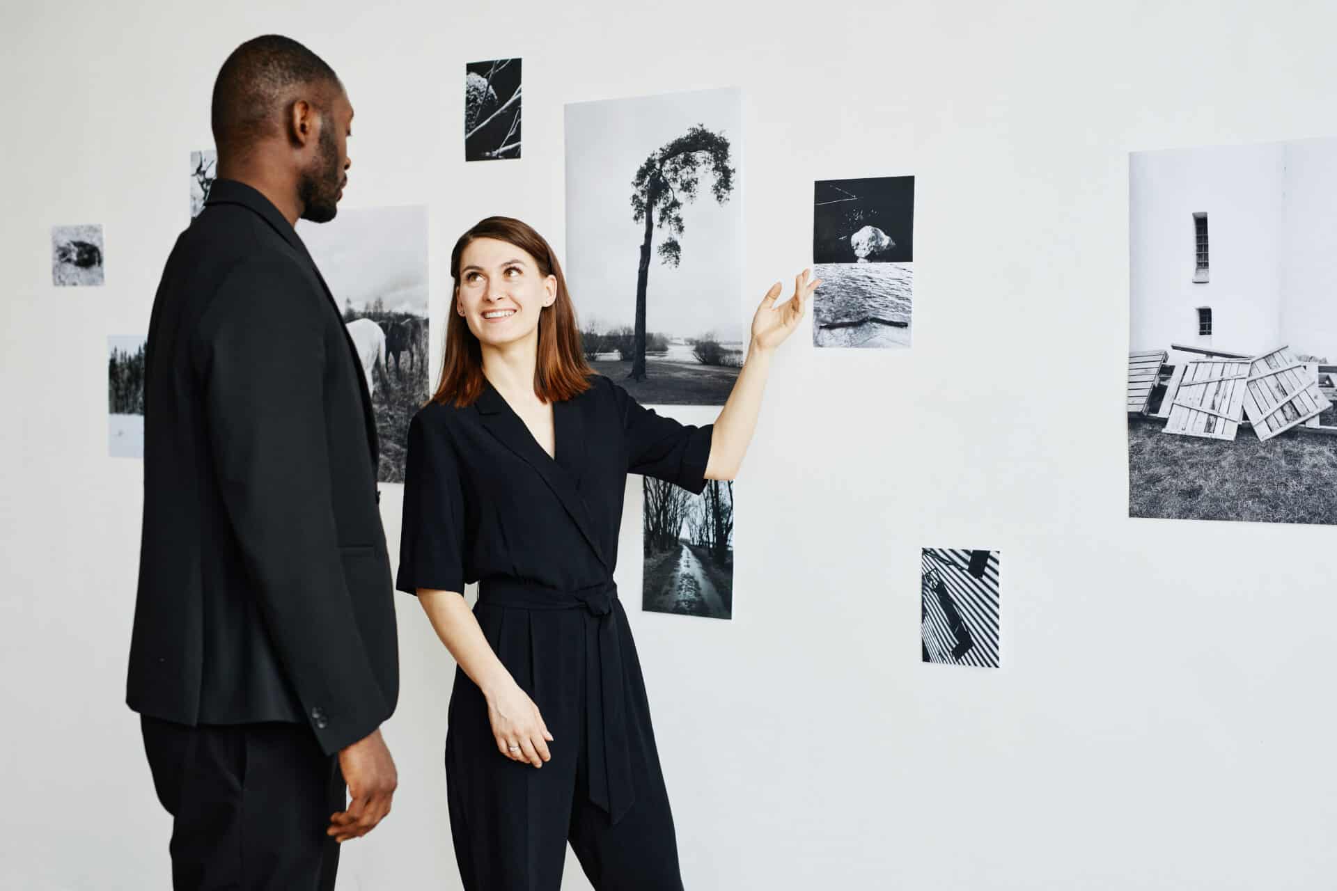 Two people looking at black and white photography images hanging on a wall.