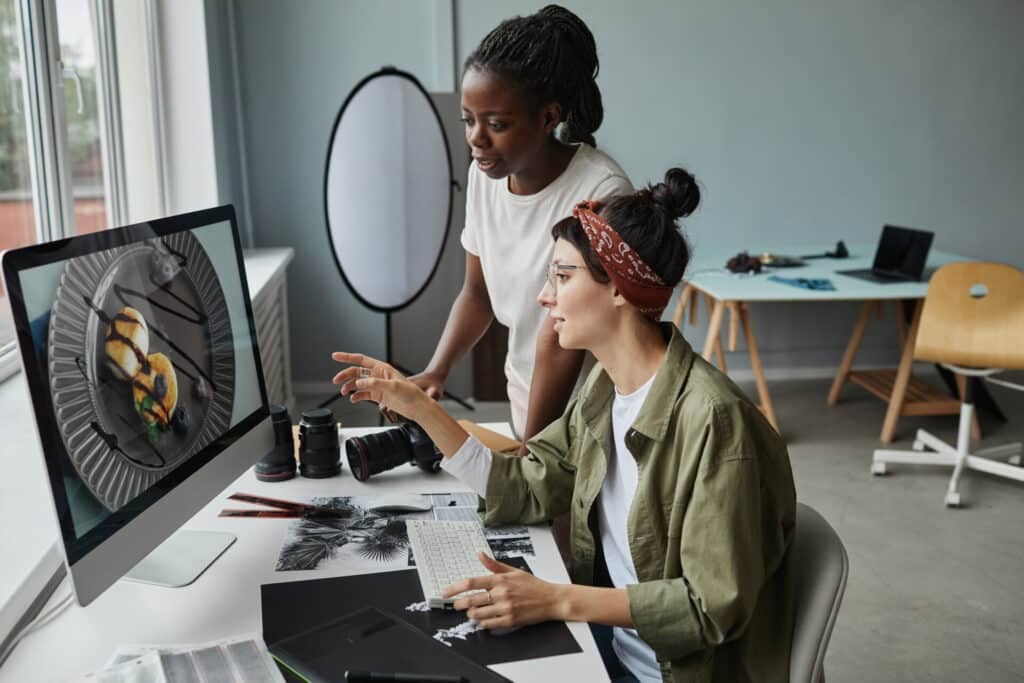 Two women editing images on a computer.