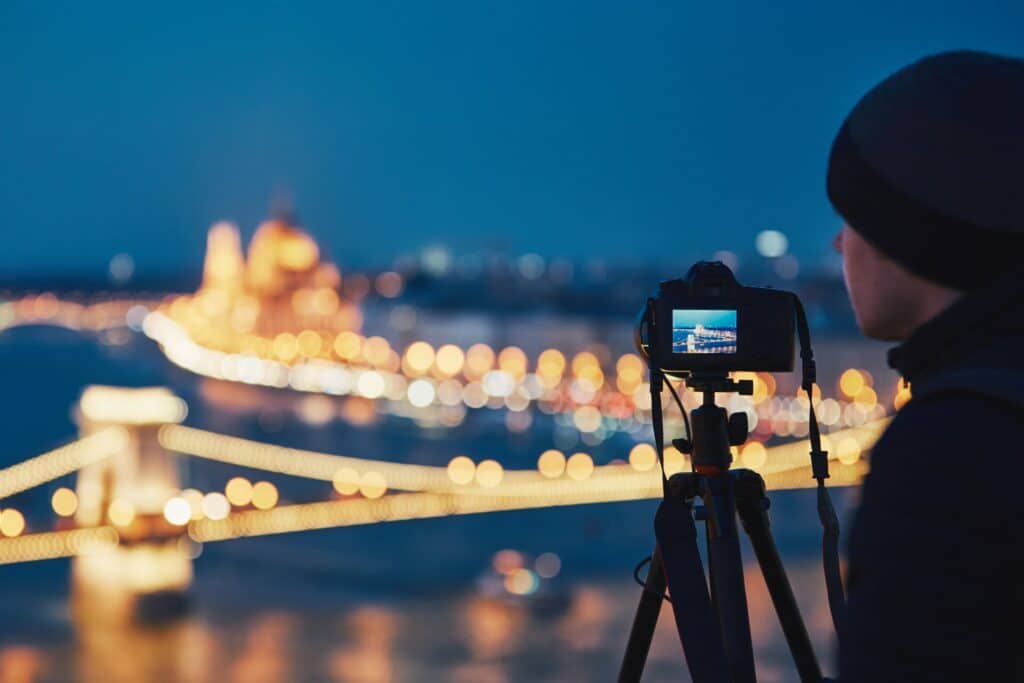 A man with a camera on a tripod taking photos of a city.