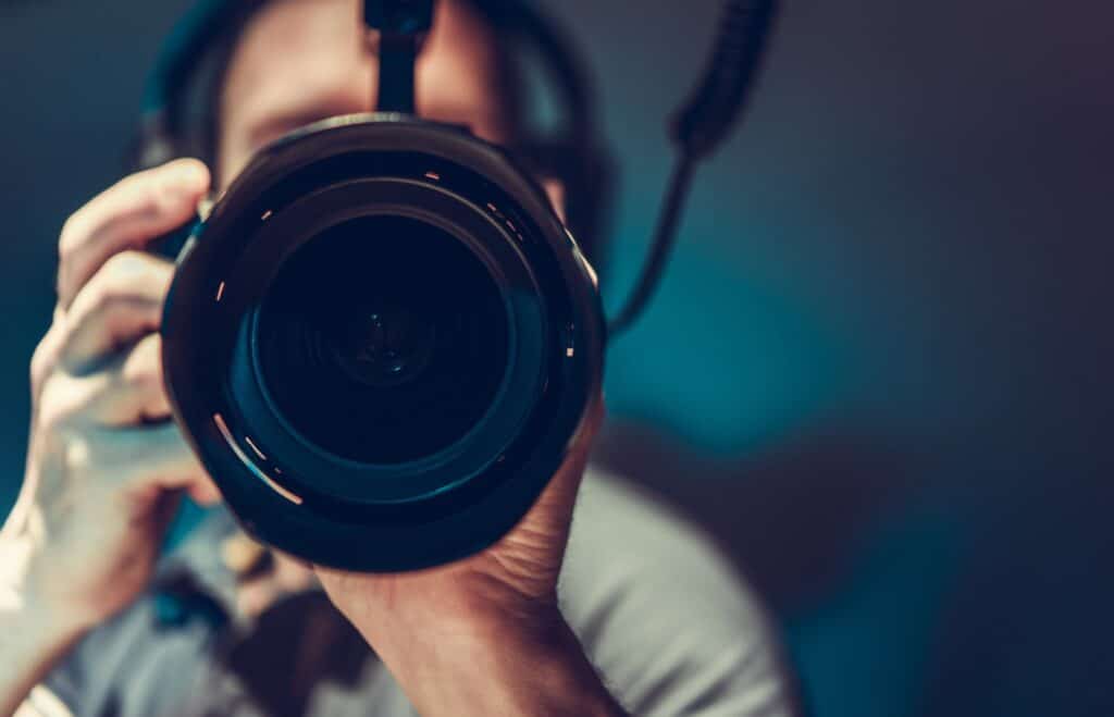 A close-up shot of a man holding a camera with a large lens. What to look for when buying a camera.