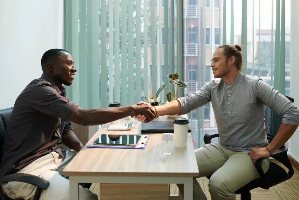 Two men shaking hands at a desk. 