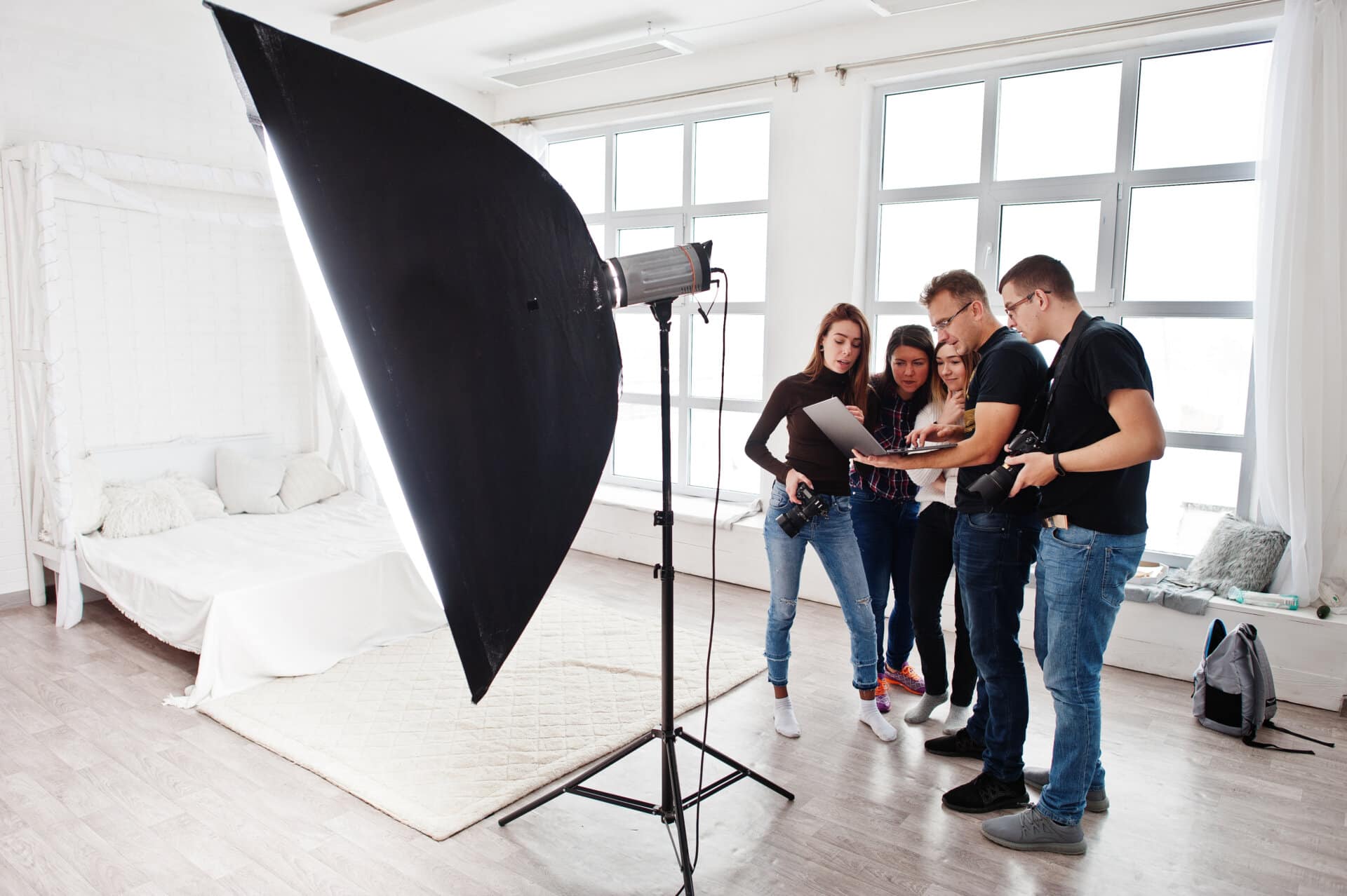 Five people gathered around a laptop at a photography set.