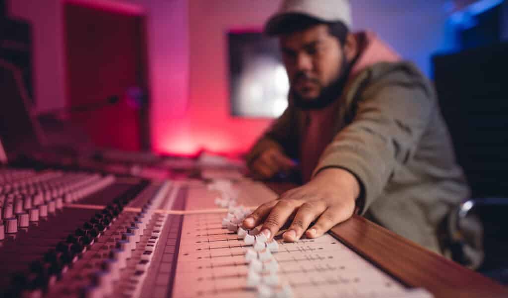 A student learning how to become a music producer at a music production school using a soundboard.